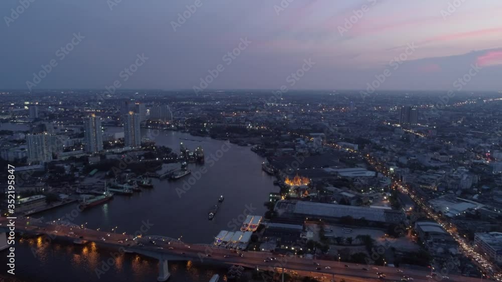 Aerial shot of vehicles on bridge over river in city against sky, drone flying forward over cityscape at dusk - Bangkok, Thailand Aerial shot of vehicles on bridge over river in city against sky, drone flying forward over cityscape at dusk - Bangkok, Thailand