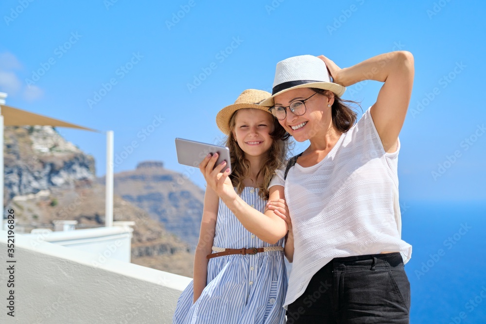 Happy tourists mother and daughter child taking selfie photo, Santorini island