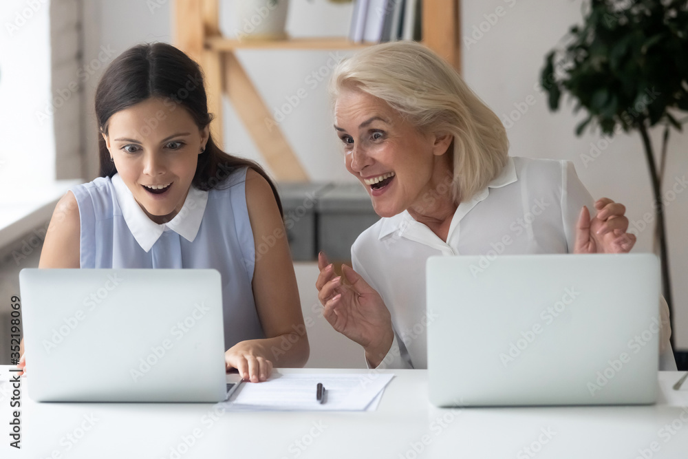 Overjoyed diverse female employees feel excited winning online business lottery on laptop, happy woman colleagues stunned surprised by unexpected shared team work results, reward, success concept Overjoyed diverse female employees feel excited winning online business lottery on laptop, happy woman colleagues stunned surprised by unexpected shared team work results, reward, success concept
