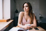 Thoughtful young woman with cup of coffee in kitchen