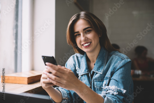 Cheerful woman browsing smartphone in cafe