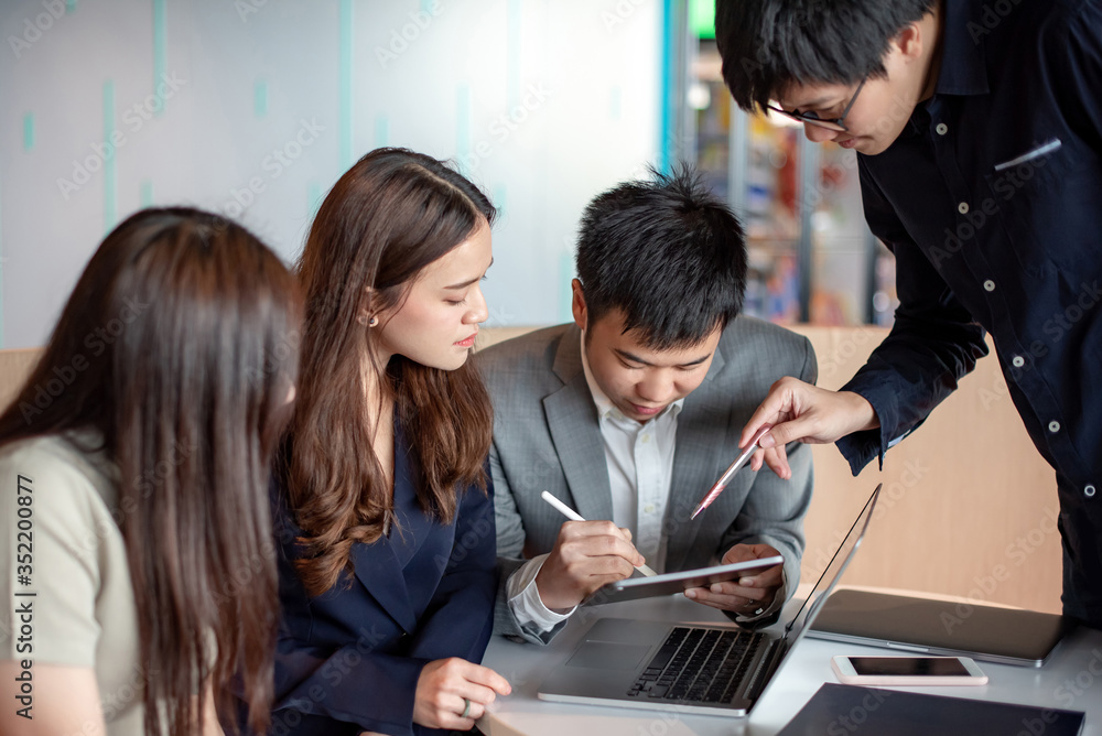 Business meeting and teamwork concept. Asian colleagues discussing about project report using laptop computer and digital tablet at workplace. Coworkers team brainstorming ideas in office boardroom. Business meeting and teamwork concept. Asian colleagues discussing about project report using laptop computer and digital tablet at workplace. Coworkers team brainstorming ideas in office boardroom.