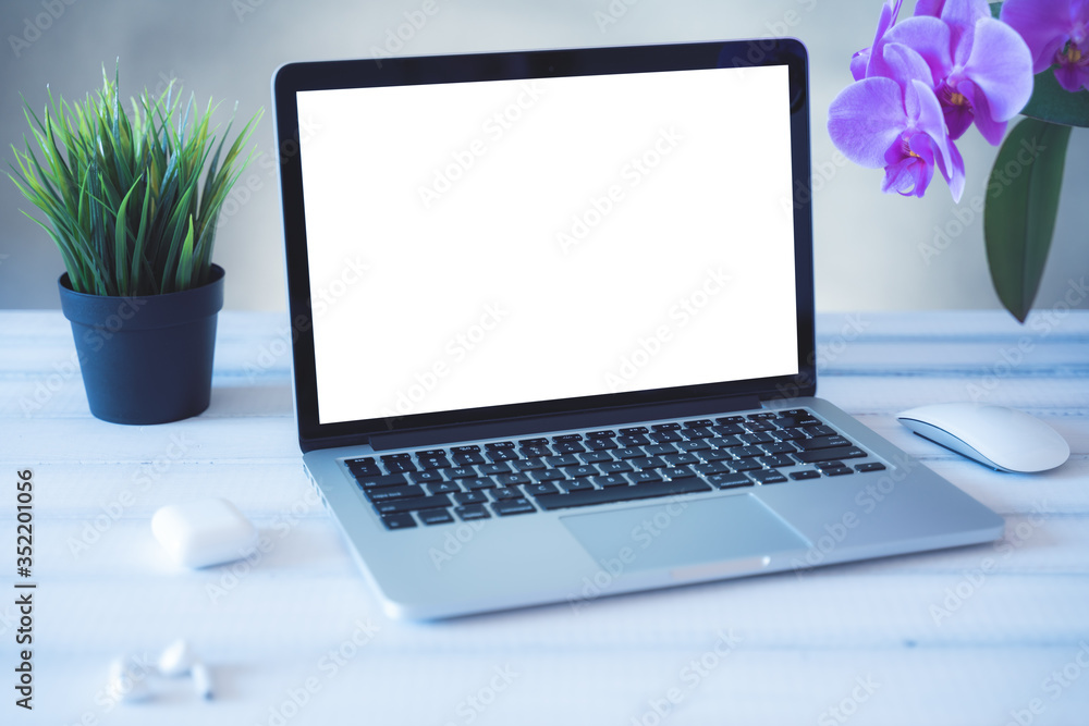 Fototapeta premium Laptop computer white blank screen on work table front view. Copy space, home and office workspace concept, laptop mockup.