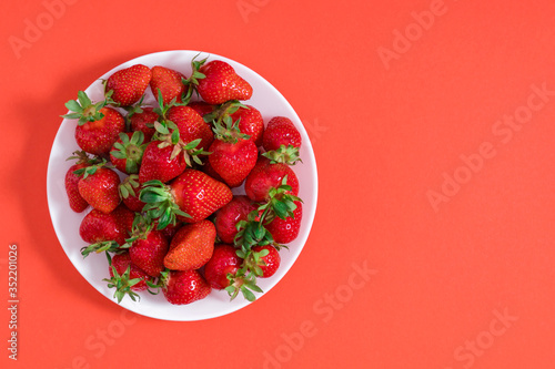 Strawberry on white plate. juicy strawberries on red background. Flat lay, top view, copy space