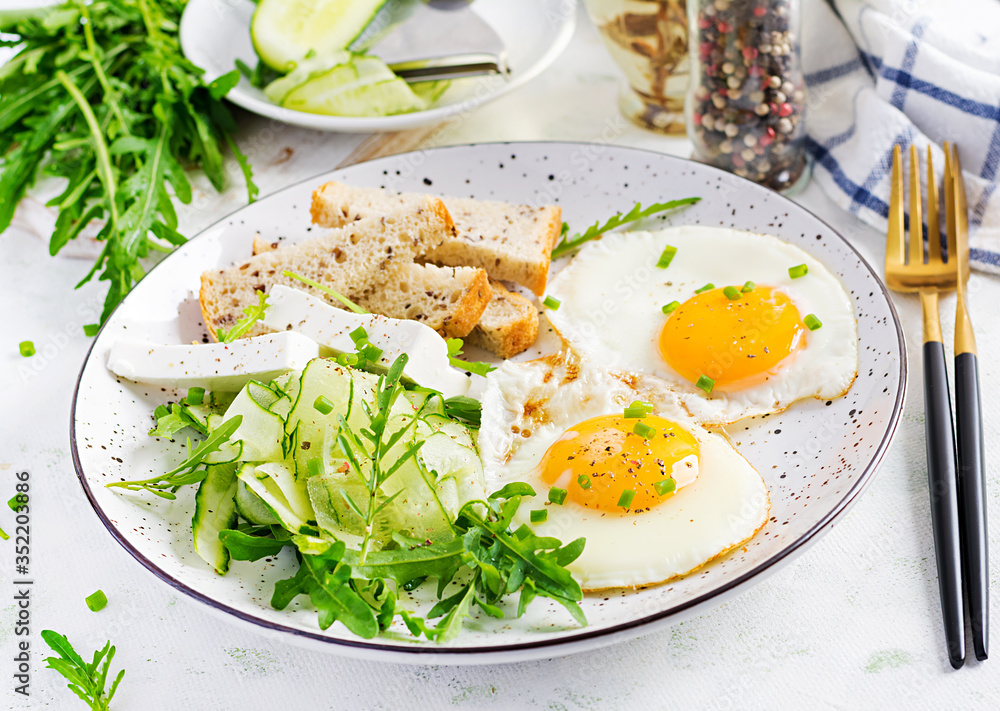 English breakfast - fried eggs, feta cheese, cucumber and arugula. American food. English breakfast - fried eggs, feta cheese, cucumber and arugula. American food.