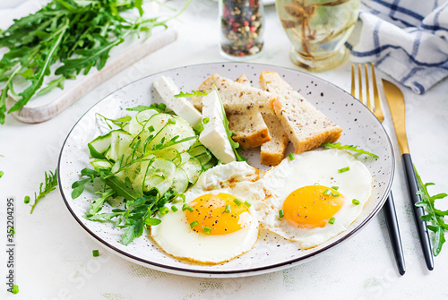 English breakfast - fried eggs, feta cheese, cucumber and arugula. American food.