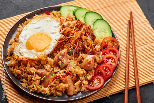 Bild auf Leinwand Nasi Goreng - Indonesian Chicken Fried Rice on a black plate on dark slate backdrop