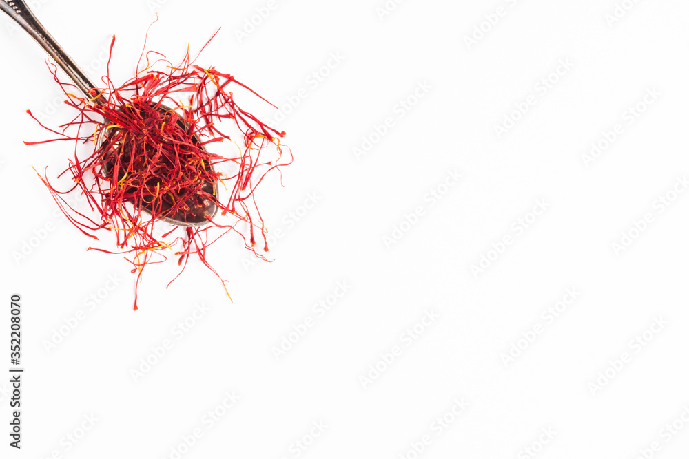 Fototapeta premium Saffron in a metal spoon. Spicy seasoning isolated on white top view.