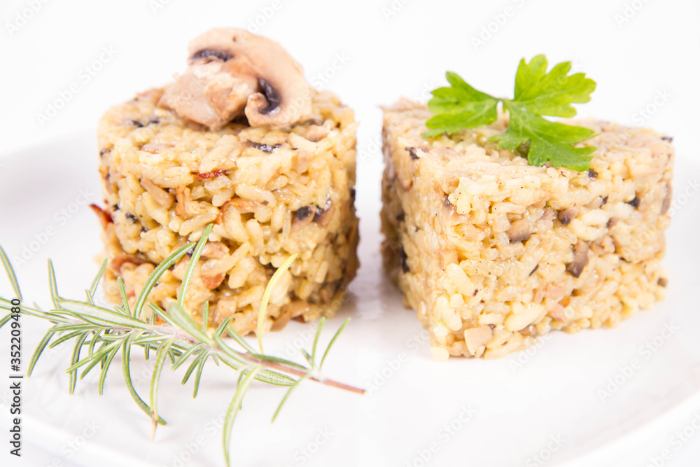 Risotto with button mushroom and bacon - two portions of different shape, on a plate on a white background Risotto with button mushroom and bacon - two portions of different shape, on a plate on a white background