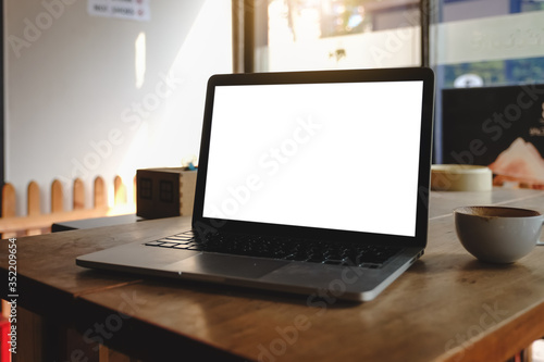 Mockup image of laptop with blank  screen on wooden table in modern loft cafe.