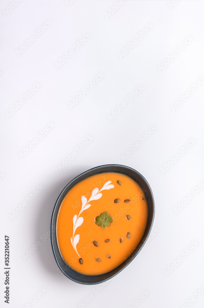 Obraz premium Homemade cream of pumpkin soup with sour cream sauce and pumpkin seeds. White background.