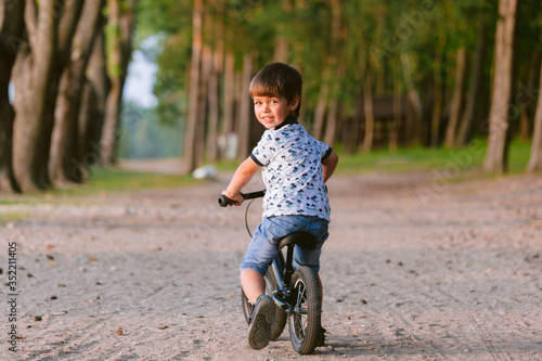 Cute little boy on balance bike. Kid on bicycle. Preschooler learning to balance on run bicycle. Sport for kids. Backview