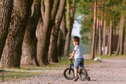 Cute little boy on balance bike. Kid on bicycle. Preschooler learning to balance on run bicycle. Sport for kids. Backview © beatleoff