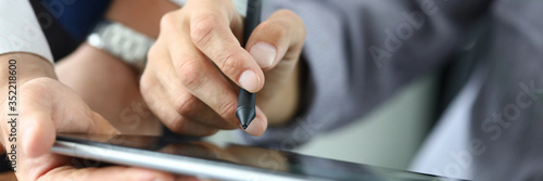 Man holds stylus and puts signature on tablet