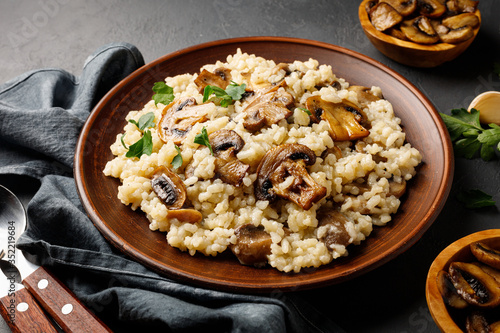 A dish of Italian cuisine - risotto from rice and mushrooms in a brown plate.