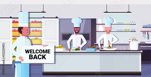 chef cook holding welcome back sign board coronavirus quarantine is ending victory over covid-19 concept restaurant kitchen interior horizontal portrait vector illustration