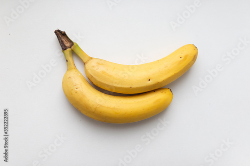 Two yellow ripe bananas on a white background. The food photos