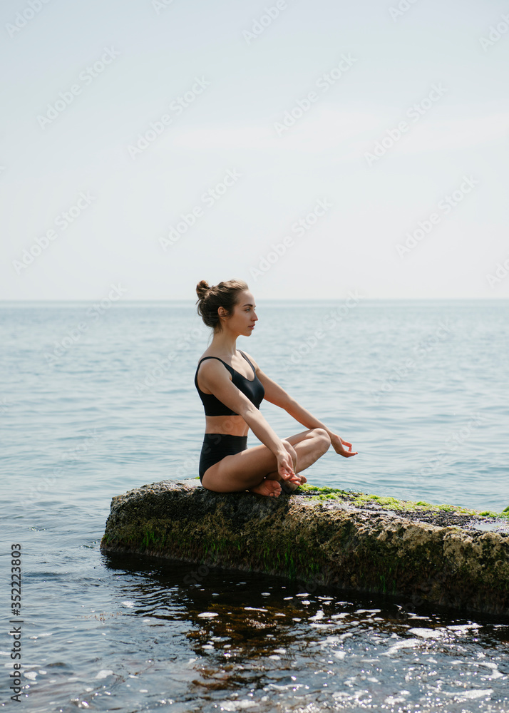 Woman practicing yoga sitting in lotus pose at seaside 
