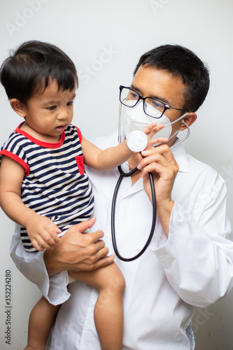 happy asian male doctor examining baby boy with stethoscope exam