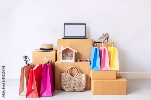 Colorful shopping bag with stack of cardboard boxes and fashion items at home, Website online shopping concept with copy space © Kittiphan