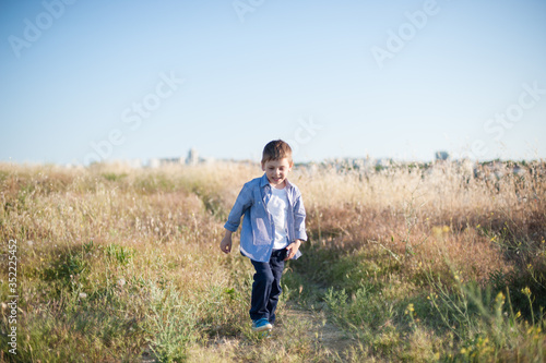 funny small active boy in shirt walking in outdoor summer nature field © ruslanshug