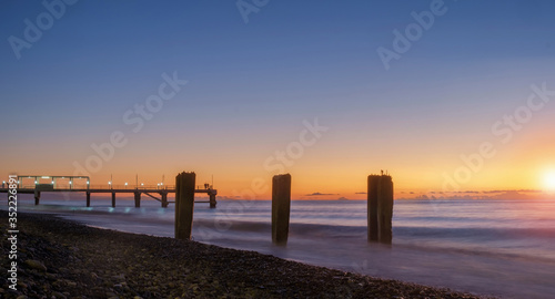 Colorful  sunset on a calm sea with pier at the background