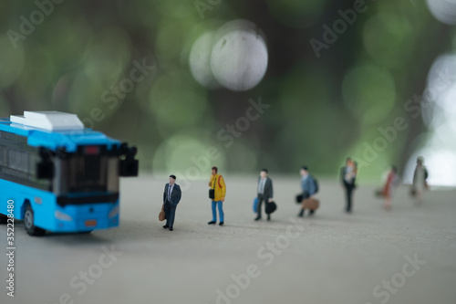 Miniature people in public during go to bus and keep distance in public society people.