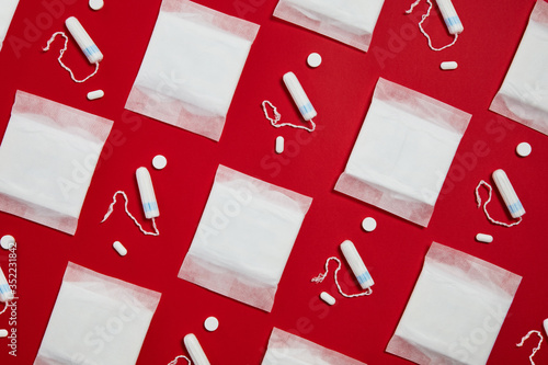 Pattern with white sanitary cotton pads and tampons isolated on red background. Feminine hygiene products