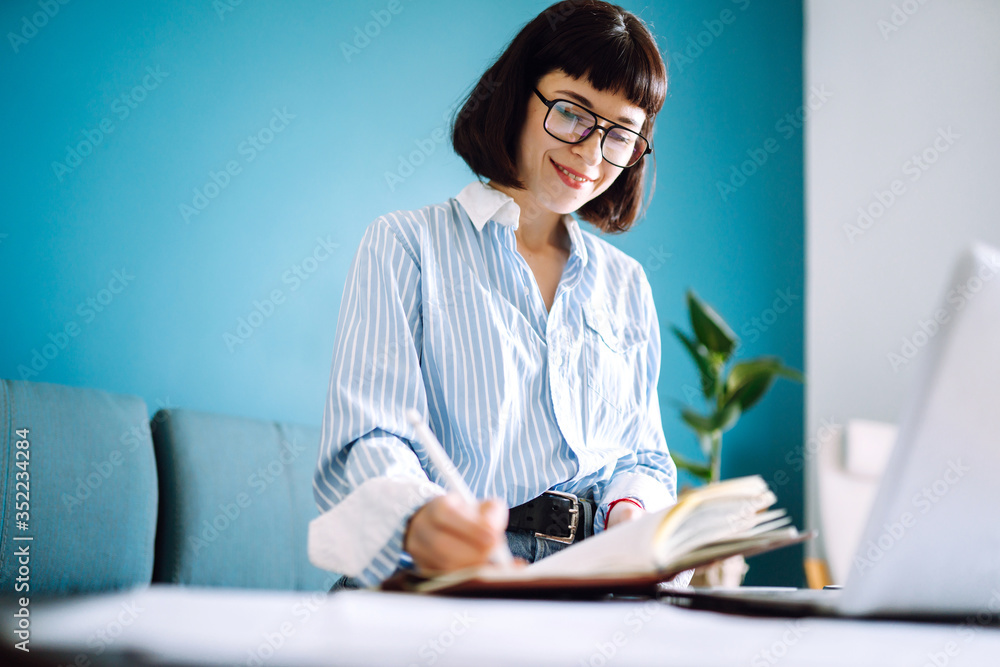 Beautiful woman at home writing and working with diary. Freelance and remote work concept. Beautiful woman at home writing and working with diary. Freelance and remote work concept.