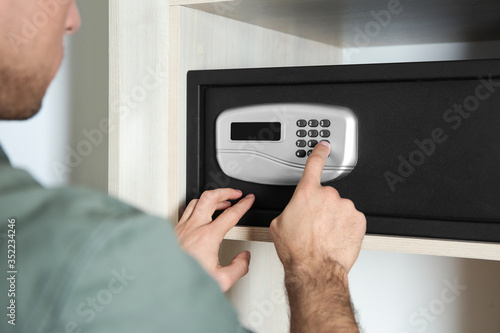 Man opening black steel safe with electronic lock at hotel, closeup