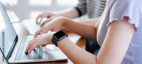 Cropped shot of young couple typing on computer during working day in home office. Working at home concept