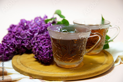 
two tea cups and a branch of lilac with green leaves