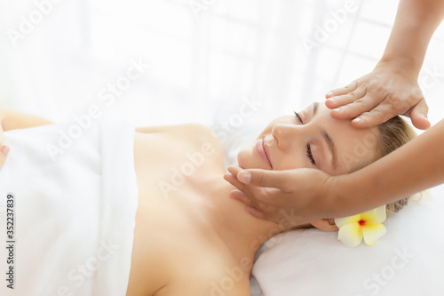 Beauty woman having massage on face  head on spa bed at spa salon with smile face. Massage therapist massage customer face  rejuvenating look younger facial skin. spa treatment. Comfortable copy space