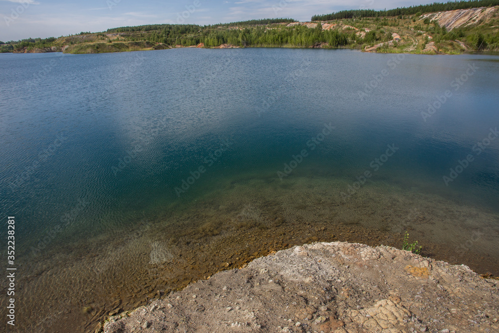 Flooded kaolin clay open pit quarry with blue water lake