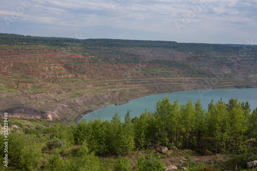 Abandoned coal ore quarry open pit flooded with blue water