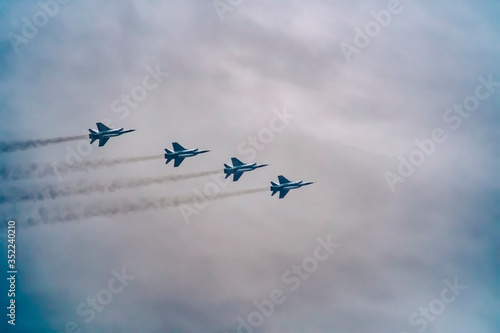 Military fighter aircraft flying in a simple construction against a background of white sky and clouds