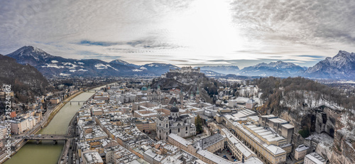 Panoramic aerial drone shot view of snowy salzburg city center with view of Cathdrals and fortress in winter photo