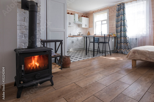 Fotografie Interior of a bright studio room with a Scandinavian style fireplace in a private house, where the living room is combined with the kitchen