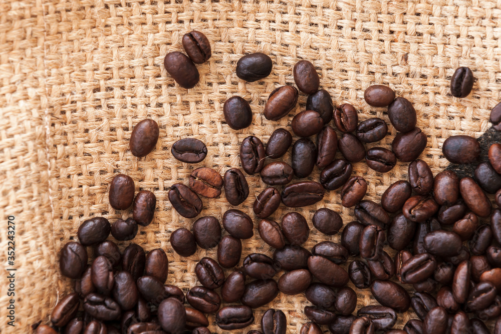 Roasted coffee beans are on jute bag fabric. Flat lay Roasted coffee beans are on jute bag fabric. Flat lay