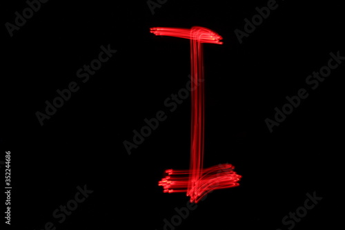 Long exposure photograph of the letter i in neon red colour fairy lights against a black background. Light painting photography. Part of an alphabet series. 