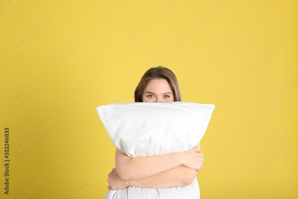 Fototapeta premium Young woman with pillow on yellow background