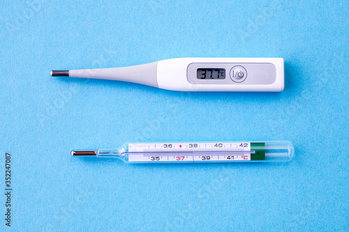 comaprison of digital and analog thermometer on blue background