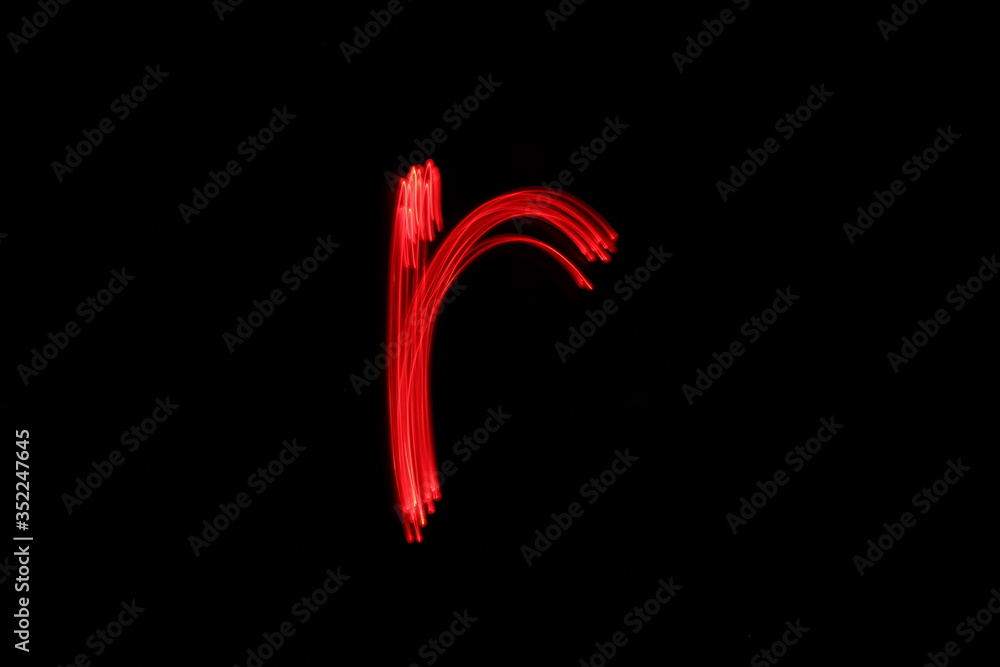 Long exposure photograph of the letter r in neon red colour fairy lights against a black background. Light painting photography. Part of an alphabet series. 