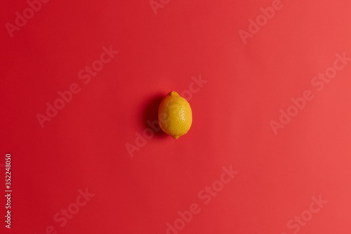 Fresh yellow sour lemon rich in vitamin C, folate, fiber and potassium to strengthen your immunity, cure cold or flu. Succulent juicy tropical citrus fruit isolated isolated on red background.