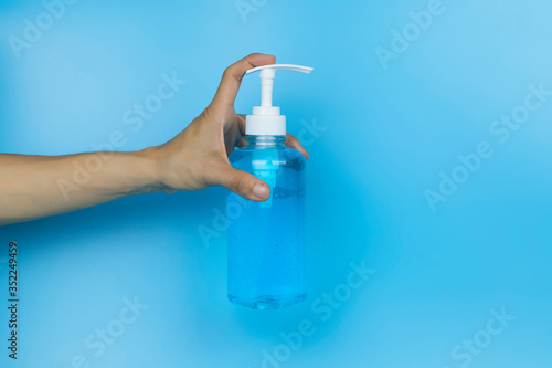 Hand holding alcohol gel. Hand holding alcohol gel sanitizer. Women hand holding alcohol gel sanitizer in pump head bottle on light blue background . With copy space.