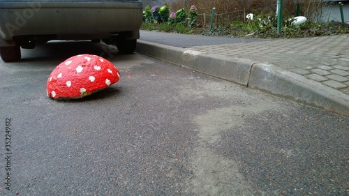 Speed ​​bumps in the form of hat of red mushroom on the pavement near the car wheels. Limiters of movement and parking auto on a road. Bright hemispheres like a ladybug. Road safety regulations.  photo