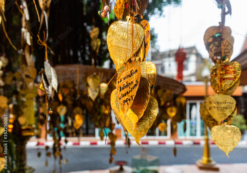 Close up view of the gold coloured leaves of the Wish Tree in the Buddhist Temple in Bangkok, Thailand. Write your wishes on the Gold Bodhi hung on tree. Cool place under a tree on a hot day. Close up view of the gold coloured leaves of the Wish Tree in the Buddhist Temple in Bangkok, Thailand. Write your wishes on the Gold Bodhi hung on tree. Cool place under a tree on a hot day.