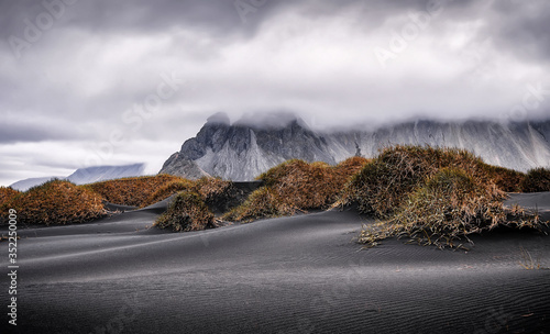 morning view on sand dunes with grass on Stokksnes cape, Vestrahorn, Iceland, Europe. Majestic Batman Mount during sunrise. Instagram filter. retro style. popular touristic attraction photo