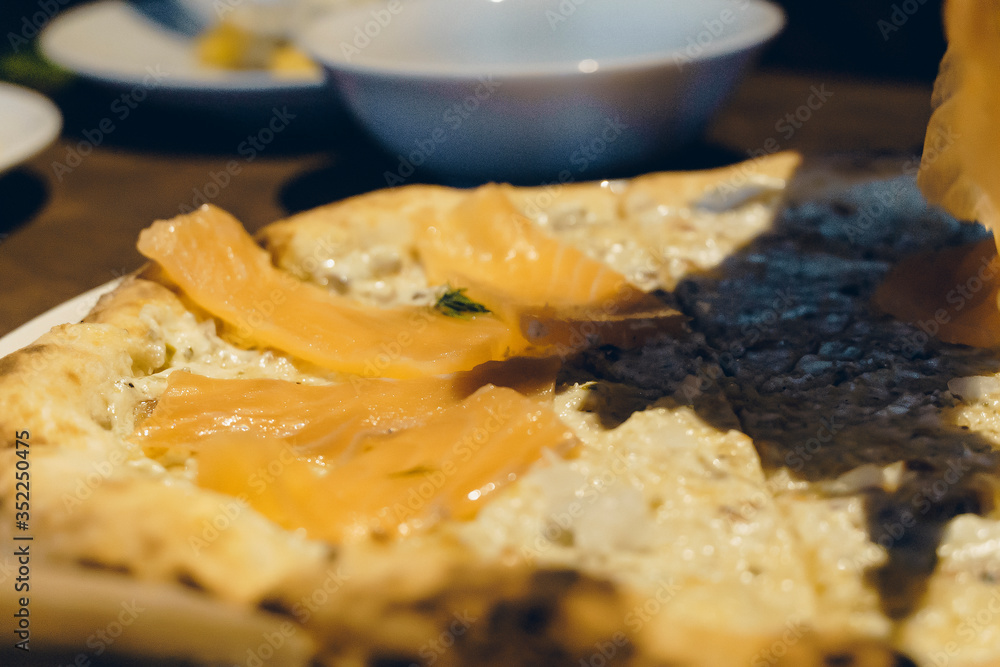 view of slice piece Salmon Sashimi pizza. Hand holding slice of pizza. view of slice piece Salmon Sashimi pizza. Hand holding slice of pizza.