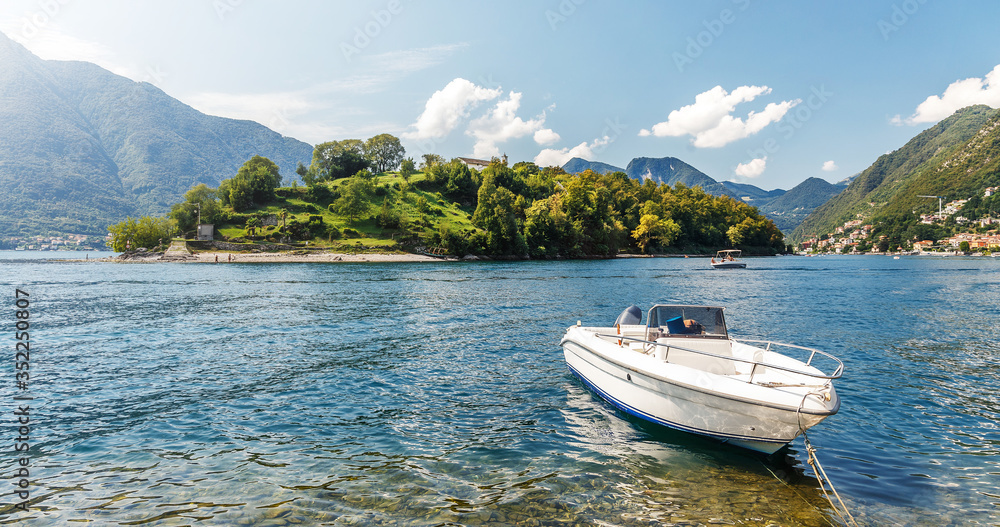 Sunny landscape of Como lake. summer view of Comacina island and luxury boat from the hiil of Ossuccio village, Province of Como, region Lombardy, Italy, Europe. popular Italyan resort.